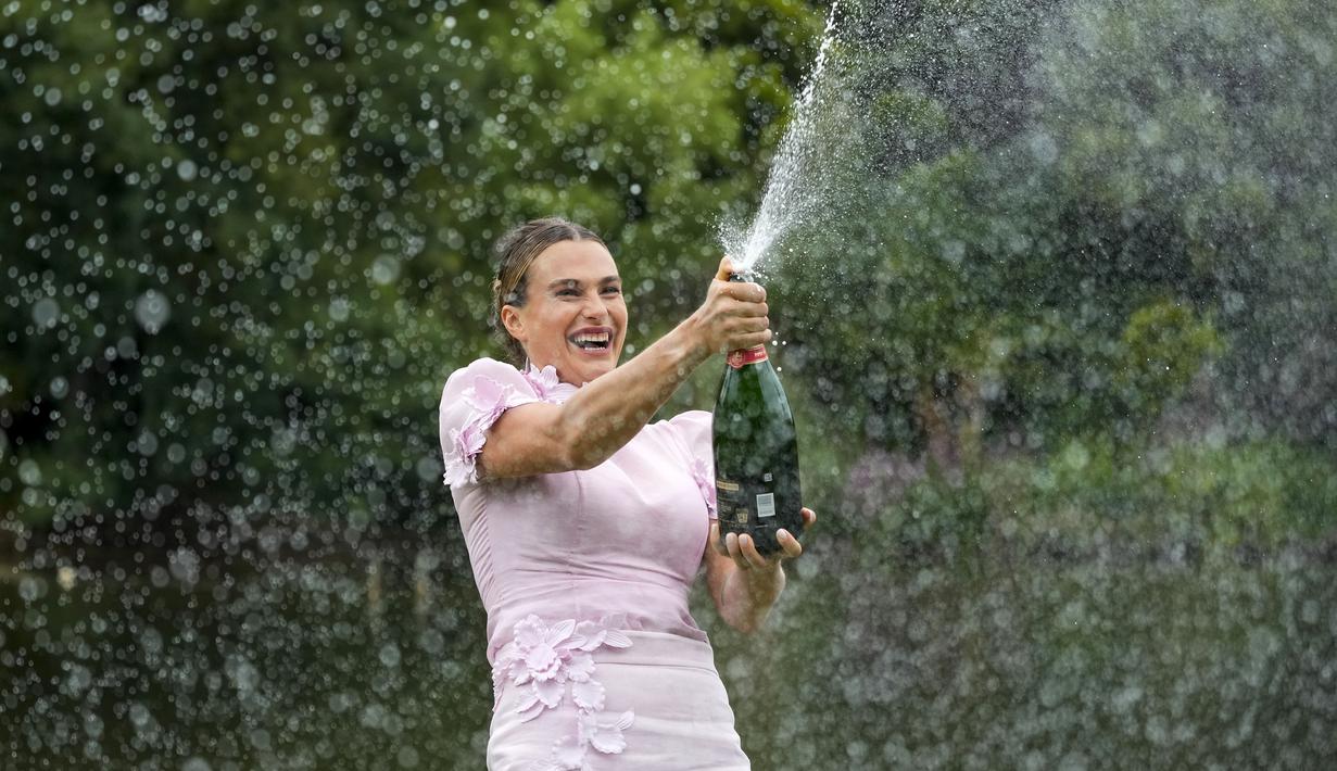 Petenis tunggal putri Belarusia, Aryna Sabalenka menyemprotkan sampanye di Royal Botanical Gardens dengan trofi Daphne Akhurst Memorial Trophy setelah menjadi juara pada Australia Open 2023 di Melbourne, Australia, Senin (30/01/2023). Sabalenka berhasil mengalahkan petenis Khazakstan, Elena Rybakina di babak final dengan skor 4-6, 6-3, 6-4. (AP Photo/Dita Alangkara)