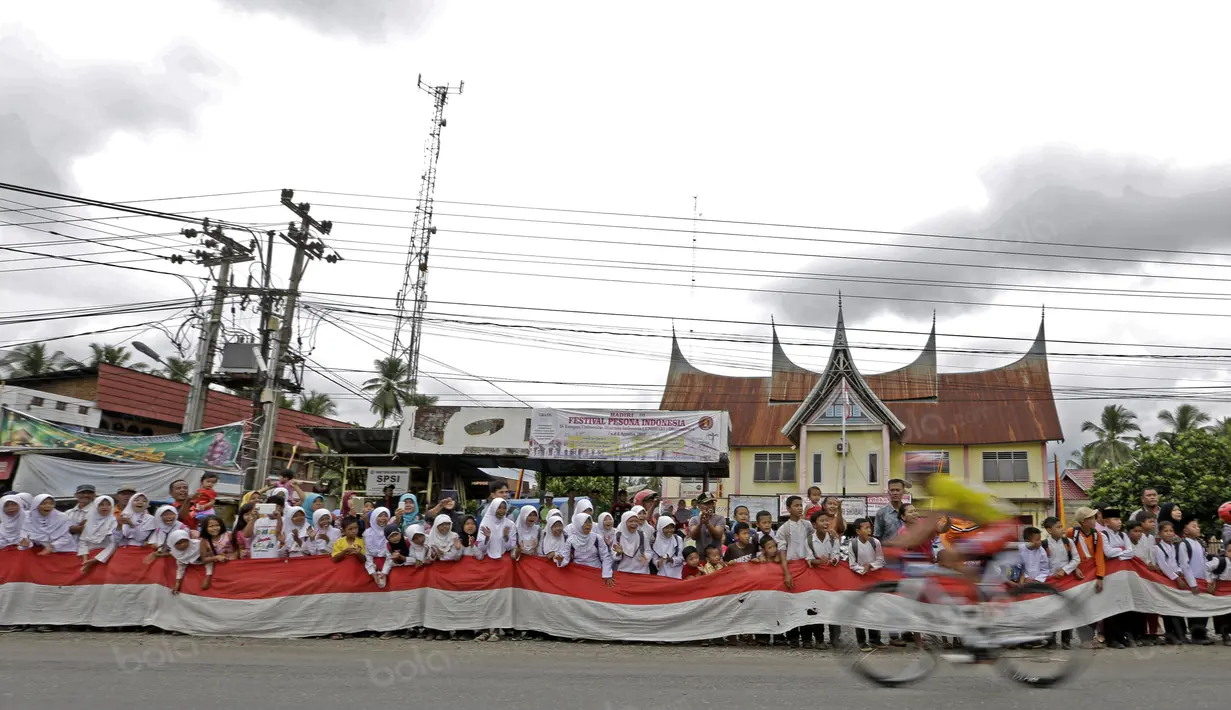 Bendera Merah-Putih sepanjang 50m dibentangkan anak-anak sekolah saat balapan Tour de Singkarak 20116 pada etape ke-7 di daerah Dharmasraya, Sumatera Barat, (12/8/2016). (Bola.com/Nicklas Hanoatubun)
