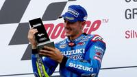 Pebalap Suzuki, Maverick Vinales, semringah menatap trofi yang diterimanya di podium usai memenangi balapan MotoGP Inggris di Sirkuit Silverstone, Inggris, 4 September 2016. (bikesportnews.com)