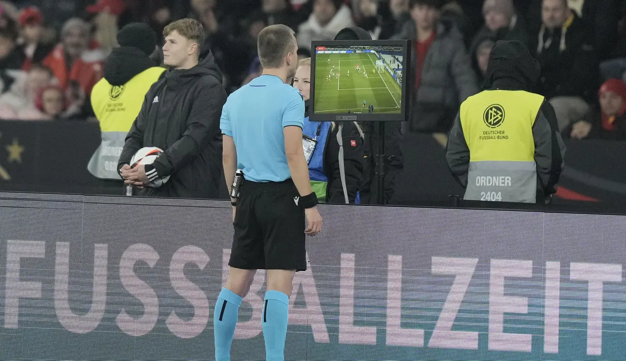 Wasit Bartosz Frankowski memeriksa rekaman VAR sebelum memberikan hadiah penalti kepada Timnas Turki saat menghadapi Timnas Jerman pada laga uji coba internasional di Olympiastadion, Berlin, Minggu (19/11/2023) dini hari WIB. (AP Photo/Markus Schreiber)