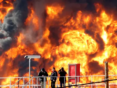 Pekerja mengamati kebakaran besar yang melanda salah satu tangki kilang minyak di Haifa, utara kota Israel, Minggu (25/12). Tidak ada korban jiwa dalam insiden yang masih belum diketahui penyebab kebakaran tersebut. (REUTERS/Baz Ratner)