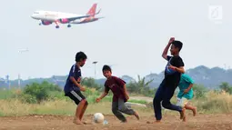 Anak-anak bermain bola di kawasan proyek perluasan landasan pacu atau Runway 3A Bandara Soekarno-Hatta (Soetta), Rawa Bokor, Tangerang, Banten, Selasa (2/7/2019). Mereka memanfaatkan lahan kosong yang belum dikerjakan pihak kontraktor untuk bermain bola. (merdeka.com/Arie Basuki)