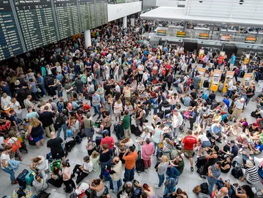 Calon penumpang berkumpul di depan papan jadwal penerbangan di Terminal 2 Bandara Munich, Sabtu (28/7). Kepolisian Jerman menutup terminal 2 bandara tersebut setelah seorang wanita dilaporkan menyusup melewati pos pemeriksaan. (MATTHIAS BALK /DPA/AFP)