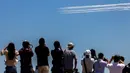 Orang-orang menonton dan mengambil gambar tim demonstrasi aerobatik Blue Impulse dari Pasukan Bela Diri Udara Jepang yang berlatih jelang pembukaan Olimpiade Tokyo 2020 di atas udara Tokyo, Jepang, Rabu (21/7/2021). Olimpiade Tokyo 2020 akan dibuka pada 23 Juli 2021. (Behrouz MEHRI/AFP)
