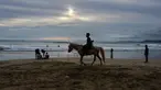 Seorang wisatawan menunggangi kuda saat berlibur Lebaran di Pantai Lhoknga, Aceh Besar, Aceh, Minggu (9/6/2019). (CHAIDEER MAHYUDDIN/AFP)