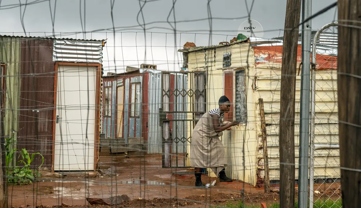 Seorang perempuan yang tinggal di pemukiman informal Vlakfontein menutup jendelanya saat hujan badai di luar Johannesburg, Senin (13/12/2021). Rata-rata kasus baru COVID-19 harian di Afrika Selatan telah meningkat selama dua minggu terakhir. (AP Photo/Jerome Delay)