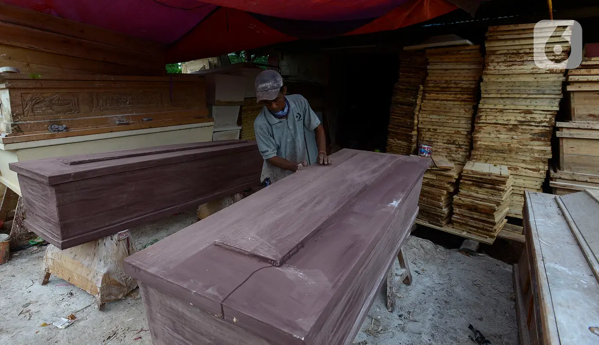Herman pengrajin peti mati sedang mengecat pelitur untuk pembuatan peti mati di Pondok Kelapa, Jakarta Timur, Rabu (6/5/2020). Peti untuk jenazah Covid-19, terbuat dari aluminium foil dengan harga Rp 900 ribu untuk ukuran dewasa dengan panjang sekitar 100-200 cm. (merdeka.com/Imam Buhori)