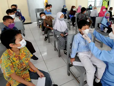 Paramedis dari Puskesmas Cinere membenahi masker murid kelas 1 saat kegiatan Bulan Imunisasi Anak Sekolah (BIAS) di SDI Al-Hidayah, Depok, Jawa Barat, Kamis (18/11/2021).  Sebanyak 100.719 siswa kelas I, II, dan V SD atau MI sederajat menjadi sasaran pemberian imunisasi. (merdeka.com/Arie Basuki)