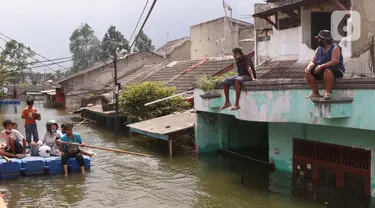 Warga melintas dengan perahu buatan saat banjir melanda perumahan Periuk Damai, Tangerang, Banten, Selasa (22/2/2021). Banjir setinggi 2,5 meter tersebut sudah terjadi selama 4 hari. (Liputan6.com/Angga Yuniar)