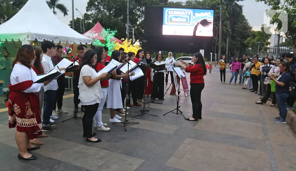 Paduan suara Christmas Carol menghibur pengguna jalan di pedestrian kawasan Sudirman, Jakarta, Rabu (18/12/2019). Pemprov DKI Jakarta menggelar perayaan Natal secara terbuka di sejumlah kawasan ruang terbuka hijau (RTH) dan protokol Ibu Kota. (Liputan6.com/Herman Zakharia)