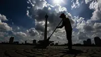 Seorang petugas dari Unit Pengelola Kawasan (UPK) Monas menyapu membersihkan sampah yang berserakan setelah perayaan malam pergantian tahun di kawasan Monas, Jakarta, Senin (1/1). (Liputan6.com/Faizal Fanani)