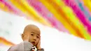 Seorang anak kecil berpakaian biksu saat upacara pemberkatan Biksu di   kuil Jogye, Seoul, Senin   (11/5/2015). Sepuluh anak diberikan kesempatan mencicipi kehidupan biksu di kuil selama dua minggu. (REUTERS/Thomas Peter)