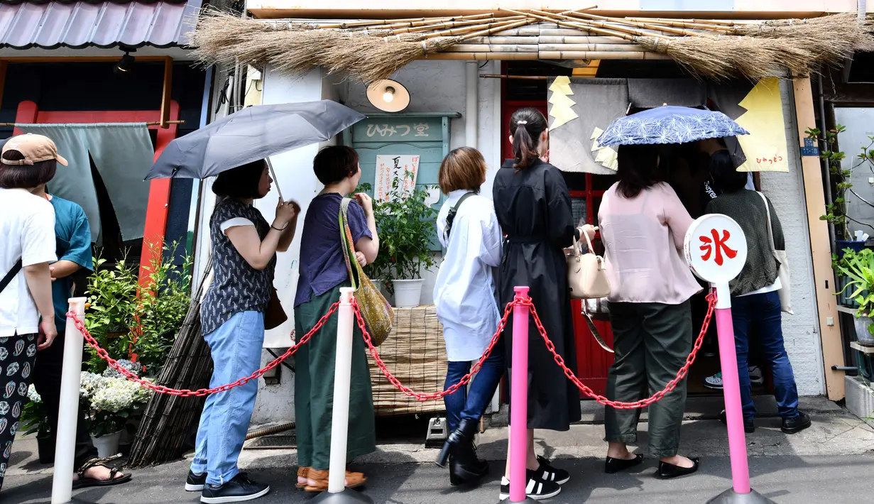 Pelanggan mengantre untuk membeli kakigori atau es serut yang menggunakan es alami di distrik Yanaka Tokyo (21/6/2019). Dilansir Japan Experience, Kakigori telah ada sejak periode Heian atau sekitar abad ke-11. (AFP Photo/Toshifumi Kitamura)