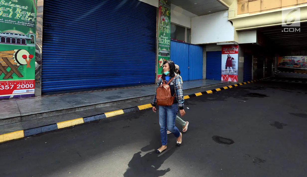 Warga melintasi sejumlah kios yang tutup di Blok B Pasar Tanah Abang, Jakarta, Selasa (27/6). Dalam rangka libur lebaran, Pasar Tanah Abang tutup mulai Minggu (25/7) hingga buka kembali pada tanggal 3 Juli 2017. (Liputan6.com/Johan Tallo)