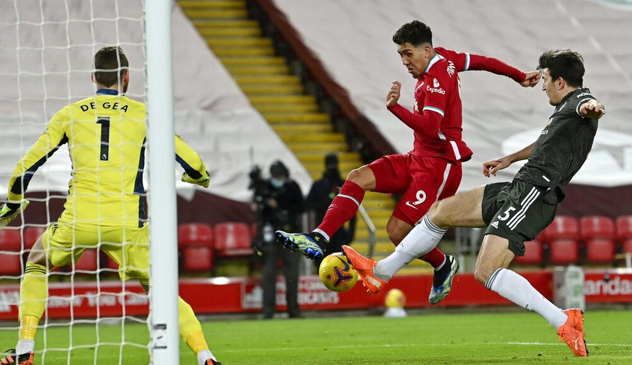 Bek Manchester United, Harry Maguire, berusaha menghalau tendangan striker Liverpool, Roberto Firmino,  pada laga Liga Inggris di Stadion Anfield, Minggu (17/1/2021). Kedua tim bermain imbang 0-0. (Paul Ellis/Pool via AP)