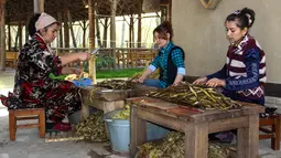Sejumlah wanita mengolah kulit pohon yang menjadi bahan pembuatan kertas tradisional di pabrik kertas Zarif Mukhtarov di desa Koni Ghil, Uzbekistan (29/3). (STR/AFP)