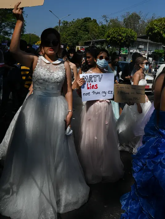 Sejumlah wanita Myanmar memakai gaun pengantin memegang plakat selama demonstrasi menentang kudeta militer 1 Februari di Yangon (10/2/2021). Aksi unjuk rasa terus digelar para demonstran yang mengabaikan larangan demonstrasi oleh militer. (AFP/ Ye Aung Thu)