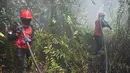 <p>Petugas pemadam kebakaran menyemprotkan air untuk memadamkan kebakaran di Kampar, provinsi Riau pada 17 September 2019. Kebakaran hutan dan lahan (karhutla) yang masih terjadi membuat sejumlah wilayah di Provinsi Riau terpapar kabut asap. (ADEK BERRY / AFP)</p>