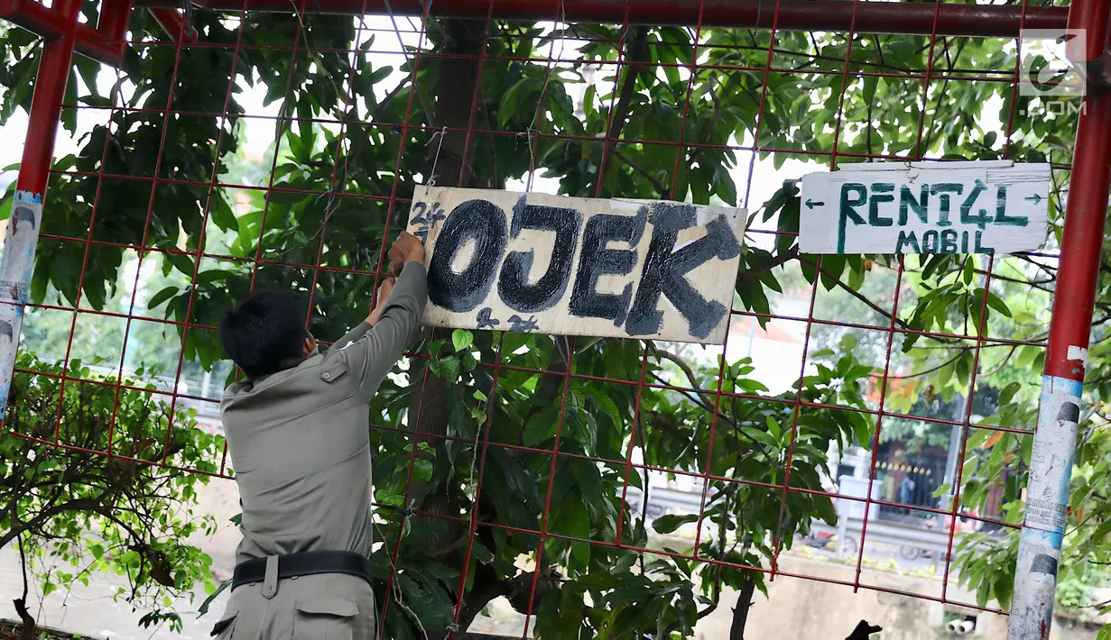 Petugas Satpol PP mencopot plang ojek saat melakukan penertiban di kawasan pusat perbelanjaan Pasar Baru, Jakarta, Rabu (21/2). Penertiban dilakukan dengan membongkar lapak PKL serta kendaraan yang parkir di trotoar. (Liputan6.com/Immanuel Antonius)