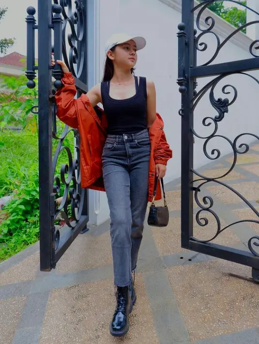 Sandrinna tampil chic dengan padu padan tanktop warna hitam, jaket warna merah, dan celana jeans warna hitam. Dia juga melengkapi penampilannya dengan boots hitam. (Instagram/sandrinna_11).