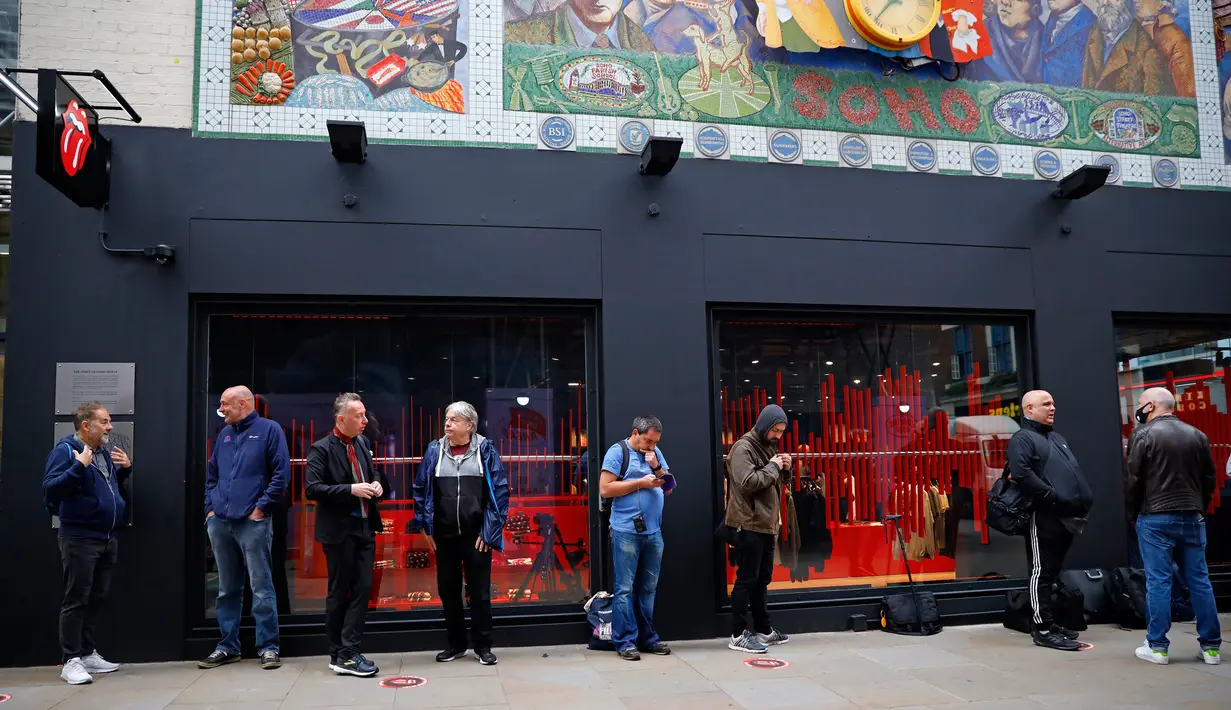 Orang-orang mengantre untuk memasuki toko andalan The Rolling Stones yang baru sebelum hari pertama pembukaannya di London, Rabu (9/9/2020). Rolling Stones membuka membuka toko pertamanya di 9 Carnaby Street. (Tolga Akmen / AFP)