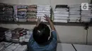 Pekerja saat merapikan kain ihram yang telah lama berada di rak toko miliknya di Jalan Raya Pondok Gede, Jakarta, Rabu (21/7/2021). (merdeka.com/Iqbal S. Nugroho)