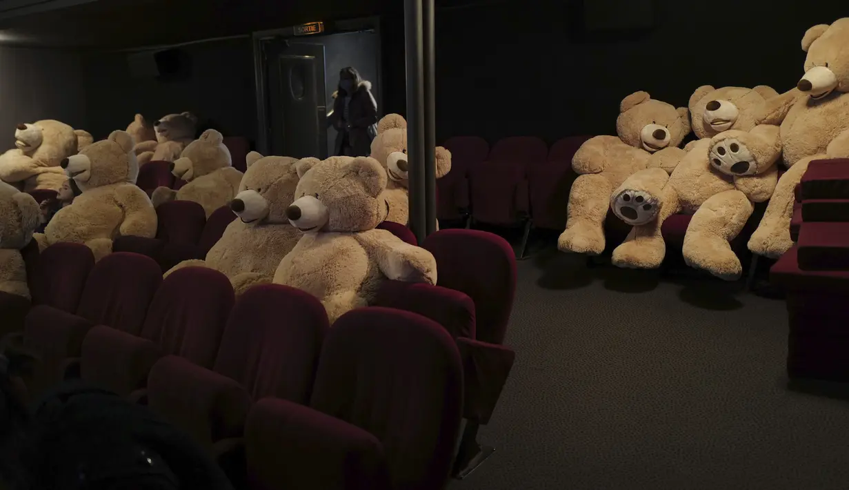 Pengunjung memasuki studio berisi boneka Teddy Bear, yang disiapkan oleh Philippe Labourel, di bioskop Les Ursulines hari pertama pembukaan kembali di Paris, Rabu (19/5/2021). Boneka-boneka beruang tersebut didedikasikan bagi anak-anak untuk mengingatkan aturan jarak sosial. (AP Photo/Francois Mori)