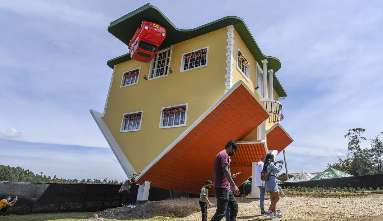 Orang-orang berjalan di luar rumah terbalik, di Guatavita, dekat Bogota, pada 29 Januari 2022. Rumah itu dirancang oleh pemiliknya, Fritz Schall dari Austria, yang tinggal di Kolombia. (Juan BARRETO / AFP)