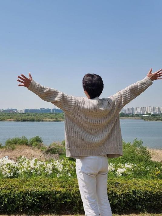 Kyuhyun mengenakan sweaternya berpose sambil membelakangi kamera. Anggota boyband tersebut mengenakan celana berwarna putih yang cocok dengan sweaternya yang berwarna terang. (Instagram/@gyuram88)