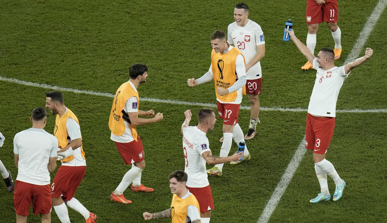 <p>Reaksi gembira para pemain Polandia setelah lolos ke babak 16 besar Piala Dunia 2022 meski kalah dengan skor 0-2 dari Argentina pada matchday ketiga Grup C yang berlangsung di Stadion 974, Doha, Kamis (01/12/2022). (AP/Hassan Ammar)</p>