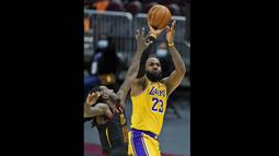 Pebasket LA Lakers, LeBron James (kanan) melempar bola ke ring dalam laga lanjutan babak reguler NBA melawan Cleveland Cavaliers di Quicken Loans Arena, Selasa (26/1/2021). (Foto: AP Photo/Tony Dejak)