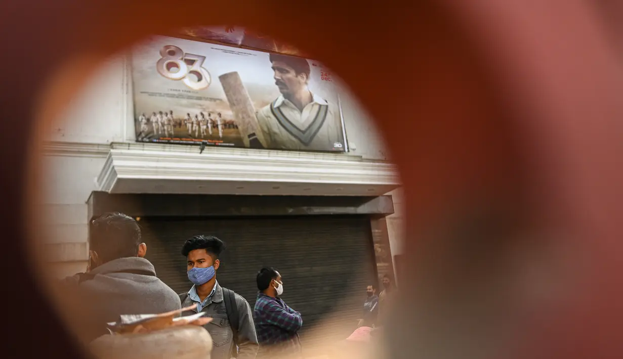 Orang-orang membeli pakaian dari kios-kios yang didirikan di luar gedung bioskop di New Delhi (29/12/2021). Pemerintah Delhi memberlakukan pembatasan fasilitas seperti gedung bioskop, multipleks, dan gym, dan lainya untuk mengekang lonjakan virus corona Covid-19. (AFP Photo/Sajjad Hussain)