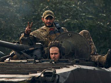 Seorang tentara Ukraina menunjukkan tanda 'V' di atas sebuah kendaraan di Izium, wilayah Kharkiv, Ukraina, 13 September 2022. Pasukan Ukraina memukul mundur tentara Rusia dari wilayah Kharkiv. (AP Photo/Kostiantyn Liberov)