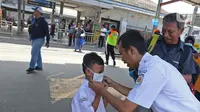 Petugas memasangkan masker ke seorang anak saat sosialisasi pencegahan virus  corona yang digelar PT KAI Daop 1 melalui Rail Clinic  di stasiun kereta Depok, Jumat (6/3/2020).  (Liputan6.com/Herman Zakharia)