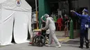 Seorang petugas kesehatan yang mengenakan pakaian pelindung mendorong pasien COVID-19 ke tenda isolasi di luar rumah sakit di Manila, Filipina, Senin (26/4/2021). Infeksi virus corona COVID-19 di Filipina melonjak melewati 1 juta pada hari Senin dalam tonggak suram terbaru. (AP Photo/Aaron Favila)