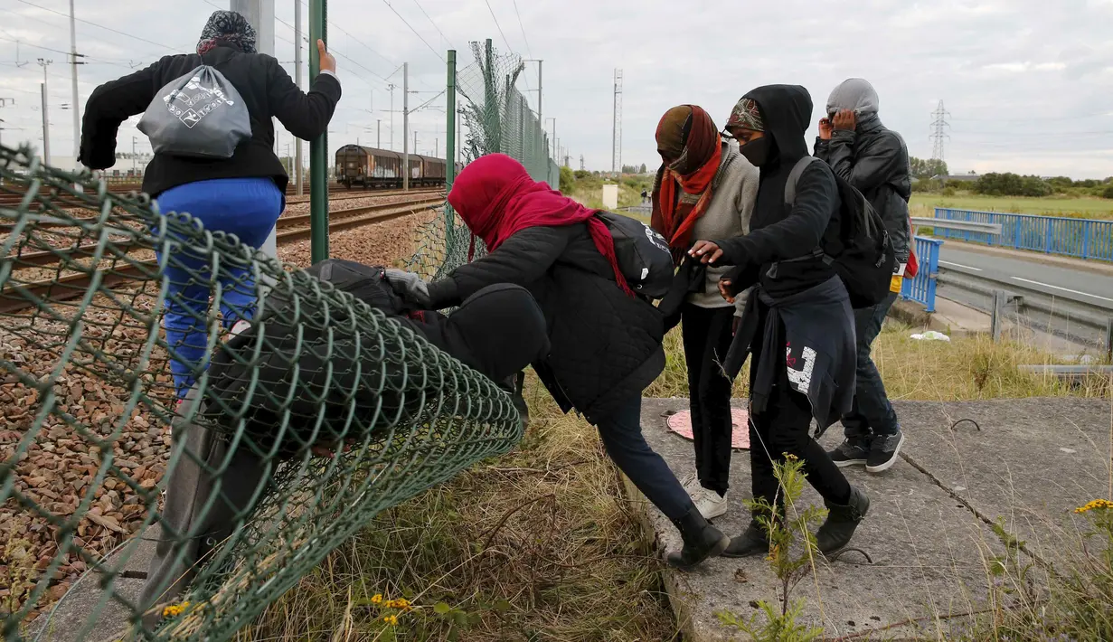 Sejumlah imigran gelap berusaha melewati pagar keamanan terminal Eurotunnel di Coquelles dekat Calais di Prancis, 29 Juli 2015. Ribuan imigran tersebut mencoba memasuki Terowongan Channel menuju Inggris melalui Prancis. (REUTERS/Pascal Rossignol)