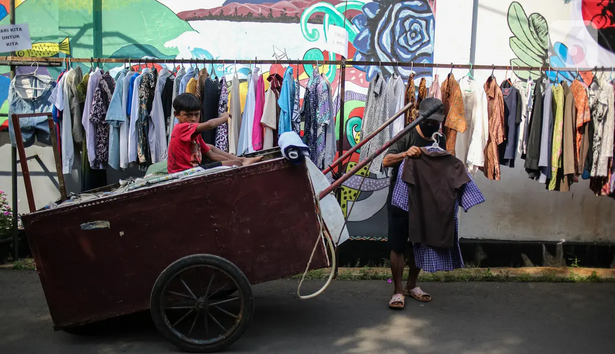 Warga memilih pakaian bekas layak pakai hasil sumbangan di RT 02 RW 04, Kelurahan Jati Padang, Jakarta, Jumat (22/5/2020). Pakaian bekas layak pakai serta sayur mayur disediakan bagi warga terdampak Pembatasan Sosial Berskala Besar (PSBB) untuk pencegahan COVID-19. (Liputan6.com/Faizal Fanani)