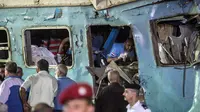 Petugas penyelamat berusaha mencari korban yang terjebak di dalam bangkai kereta usai tabrakan di Kota Alexandria, Mesir (11/8). (AFP Photo/Khaled Deouki)