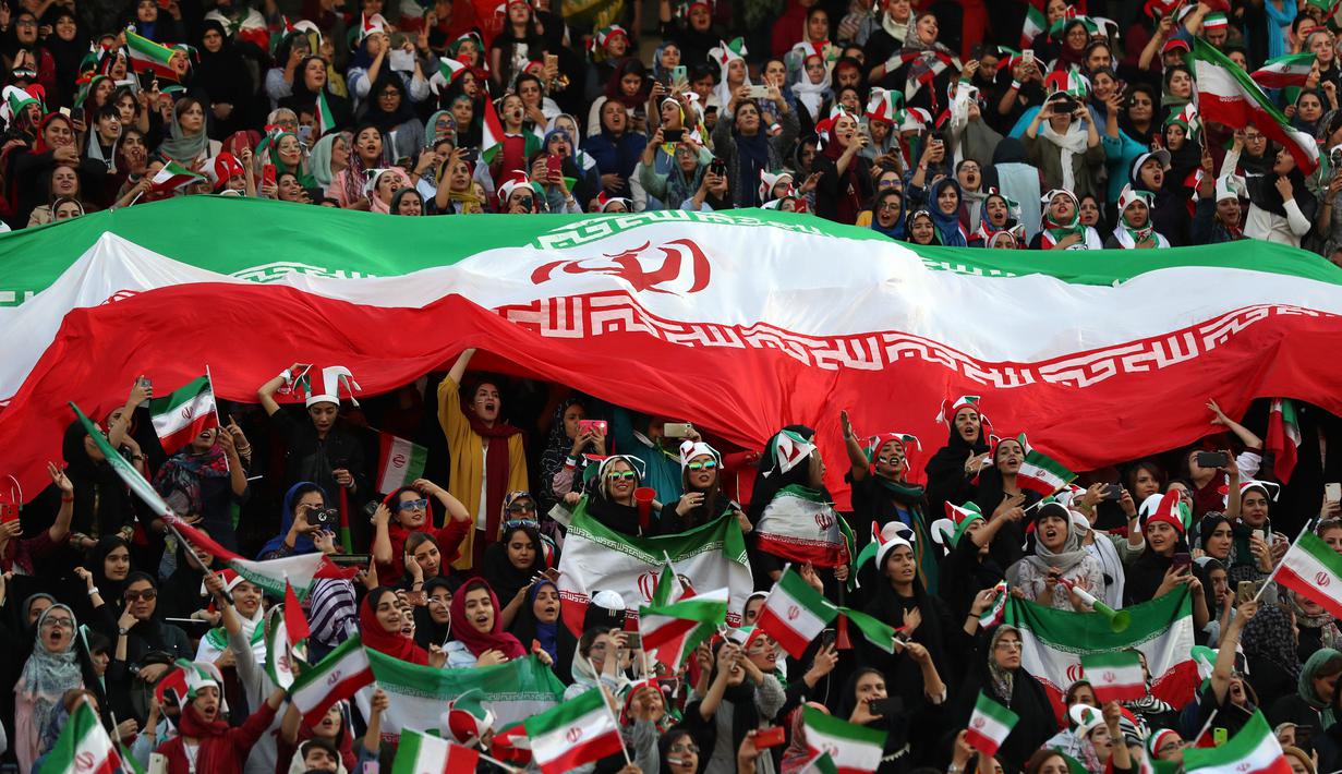 Wanita Iran bersorak sambil mengibarkan bendera negaranya saat menyaksikan laga kualifikasi Piala Dunia 2022 antara Iran dengan Kamboja di Stadion Azadi, Teheran, Iran, Kamis (10/10/2019). Wanita Iran diizinkan menonton bola ke stadion setelah seorang wanita membakar dirinya. (AP Photo/Vahid Salemi)