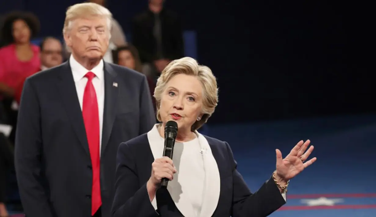 Hillary Clinton saat menjawab pertanyaan penonton dalam debat Capres AS putaran kedua, St Louis, AS, Minggu (9/10). Terlihat di belakang Hillary, Trump berekspresi aneh yang menjadi bahan ejekan di media sosial. (REUTERS/Rick Wilking)