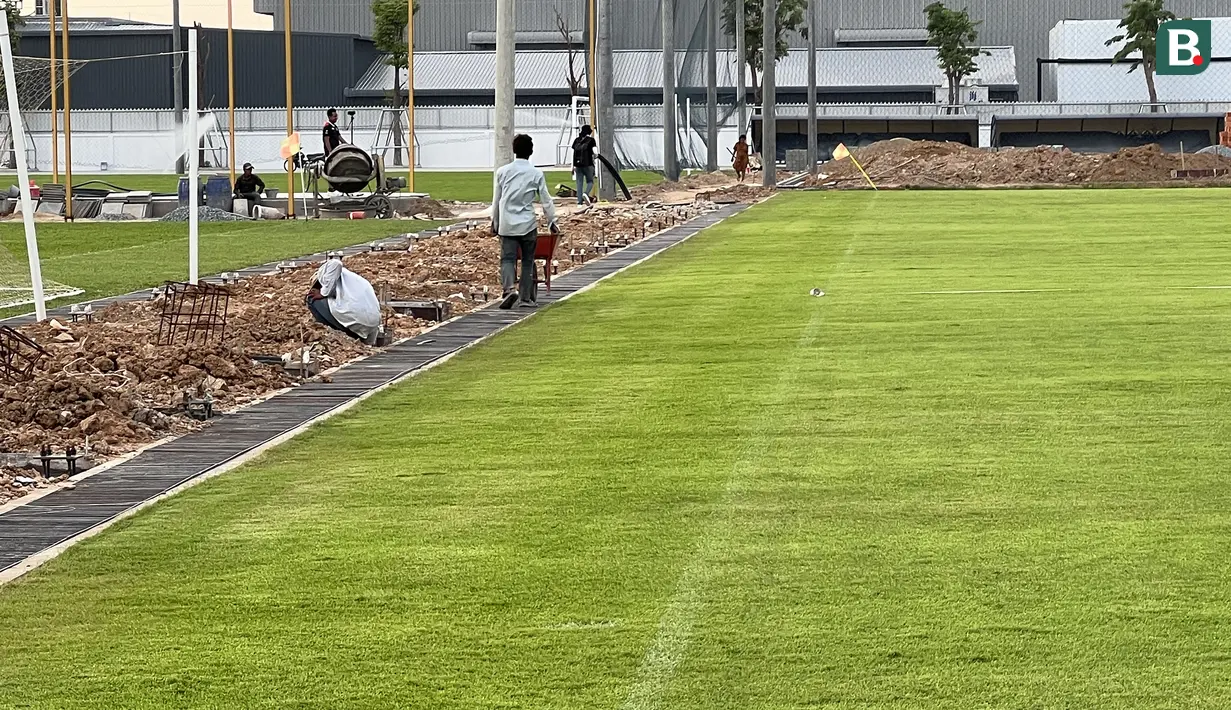 Beberapa pekerja bangunan tampak beraktivitas di pinggir lapangan dalam tahap akhir pembangunan Visakha Training Center milik Visakha FC yang tengah digunakan Timnas Indonesia U-22 menggelar sesi latihan terakhir, Rabu (3/5/2023) jelang menghadapi Myanmar pada laga kedua Grup A SEA Games 2023 yang akan digelar Kamis, 4 Mei 2023. (Bola.com/Gregah Nurikhsani)