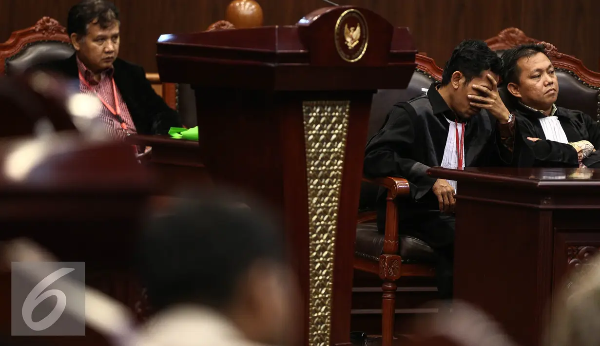 Kuasa Pemohon Muhammad Ainul Syamsu (kedua kanan) menutup muka saat mengikuti sidang terkait  gugatan terhadap Pasal 5 ayat 1 dan 2 serta pasal 44 huruf b UU ITE di Mahkamah Konstitusi, Jakarta, Rabu (7/9). (Liputan6.com/Faizal Fanani)