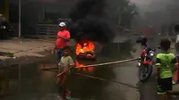 Warga membakar ban mobil bekas karena jalan di perbatasan Kabupaten Gowa dan Kota Makassar, kerap banjir dan tergenang. (Liputan6.com/Ahmad Yusran)
