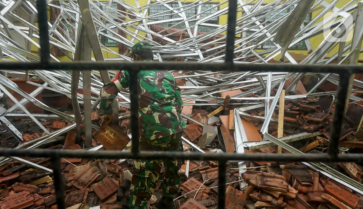 Petugas Babinsa TNI AD membersihkan reruntuhan atap yang ambruk akibat gempa di salah satu ruang kelas di MAN 2 Malang, Turen, Kabupaten Malang, Minggu (11/4/2021). Gempa bermagnitudo 6,1 yang terjadi pada Sabtu (10/9) siang menyebabkan kerusakan berat di MAN 2 Malang. (merdeka.com/Nanda F. Ibrahim)