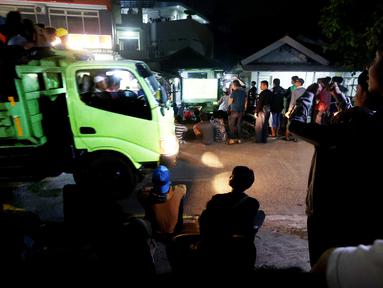 Truk melintas di tengah-tengah warga yang sedang asik nobar Timnas Indonesia U-23 vs Uzbekistan di kampung Sampora, Cisauk, Tangerang, Selasa (29/4/2024). (Bola.com/M Iqbal Ichsan)