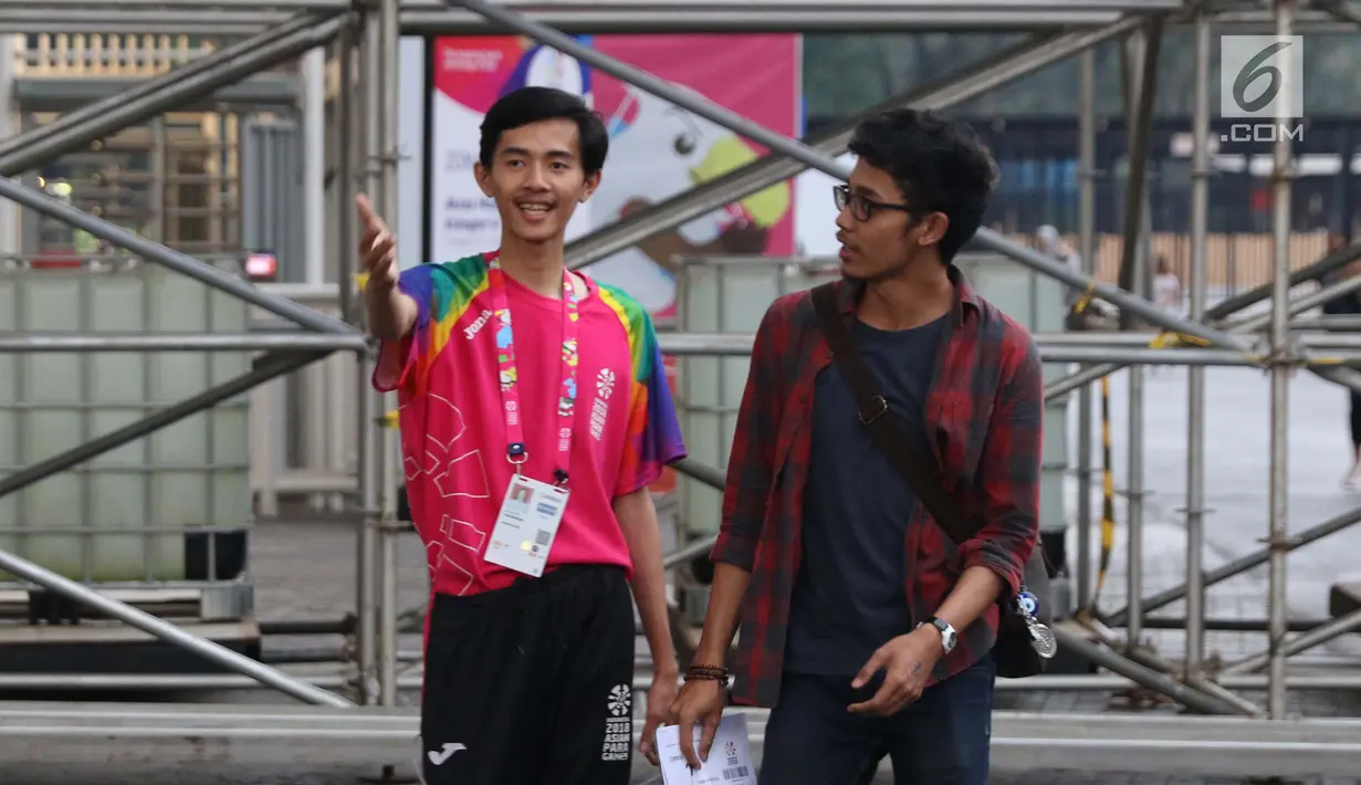 Volunteer Asian Para Games 2018 membantu pengunjung menunjukkan lokasi pintu masuk di Stadion GBK, Jakarta, Kamis (11/10). Mereka bertugas membantu kelancaran pelaksanaan Asian Para Games 2018. (Liputan6.com/Helmi Fithriansyah)