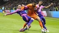 Pemain Jerman, Pascal Gross dan Benjamin Henrichs menghadang pemain Belanda, Cody gakpo, pada laga persahabatan di Stadion Deutsche Bank Park, Frankfurt, Rabu (27/3/2024). (AP Photo/Martin Meissner)
