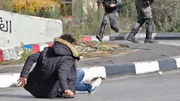 Pria Palestina terjatuh usai ditembak polisi Israel di dekat Ramallah, Tepi Barat, Jumat (15/12). Akibat pernyataan Presiden AS yang mengakui Yerusalem sebagai ibu kota Israel Situasi di perbatasan Palestina-Israel terus memanas. (AFP Photo/Oren Ziv)
