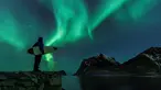 Seorang surfer melihat Cahaya Utara atau aurora borealis di Utakleiv, Norwegia utara (9/3). Aurora ini adalah sebuah peristiwa langit yang cantik berupa pancaran cahaya yang menyala-nyala di atmosfer sekitar lingkaran Arktik. (AFP/Olivier Morin)