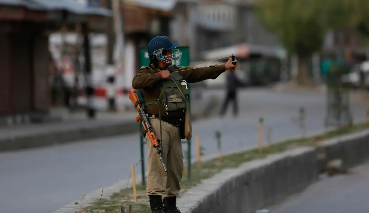 Seorang tentara paramiliter India menggunakan ketapel selama bentrok dengan pengunjuk rasa selama protes terhadap pembunuhan pemberontak di Srinagar, Kashmir yang dikuasai India, (1/4). (AP Photo / Dar Yasin)